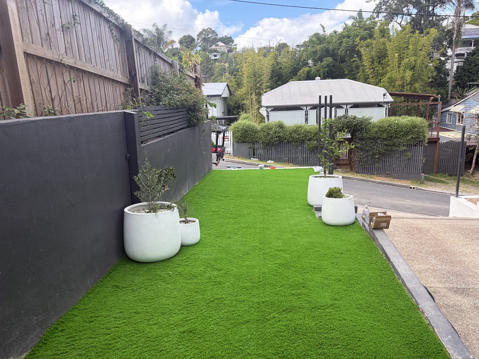 Freshly installed artificial turf and rendered retaining wall by T&M Landscapes